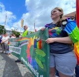 Mitglieder der Grünen stehen beim CSD in Bramsche und halten ein Banner mit Regenbogenfarben und der Aufschrift 'Vielfalt? Lieben wir!'
