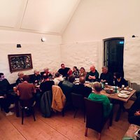 Gruppe von Personen sitzt an zwei zusammengestellten Tischen in einem Raum mit weißen Wänden und Holzboden bei der Jahreshauptversammlung der Grünen Bramsche